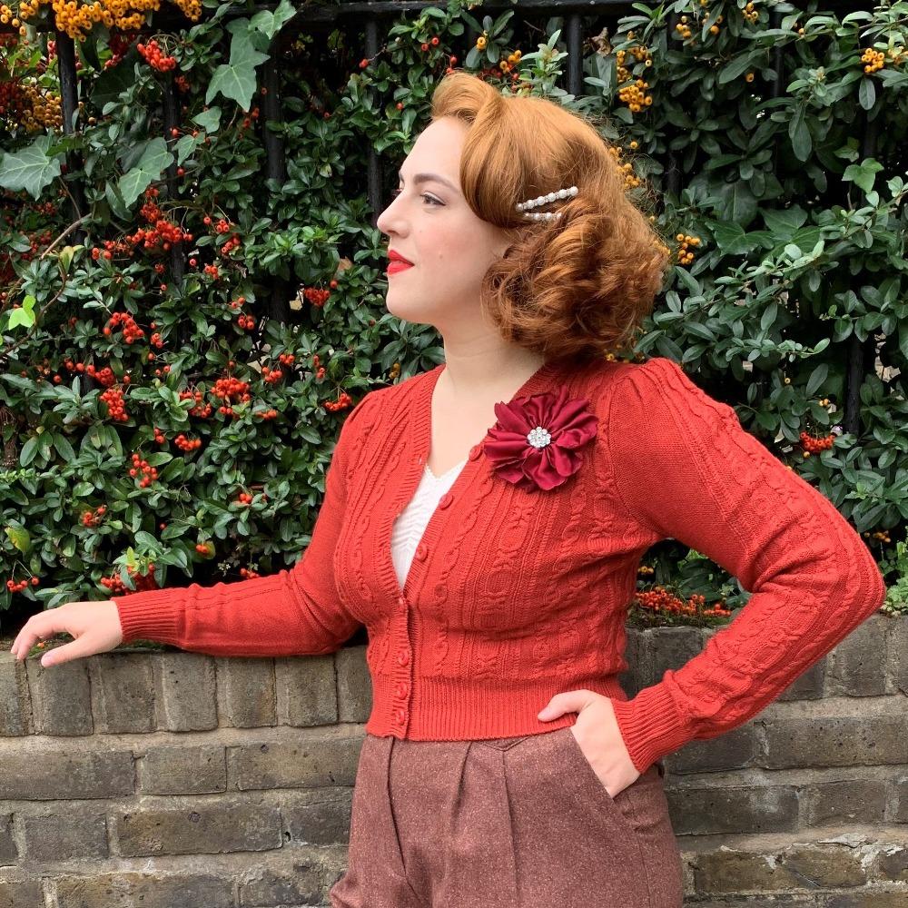 Vintage style fabric hair flower burgundy by Lovett & Co as worn by red haired model on a 1940s cropped knitted cardigan