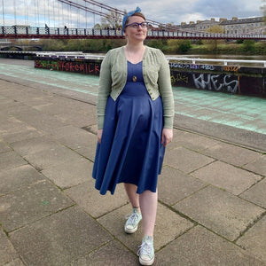 1950s Dress with pockets in blue GOTS organic cotton by Revival Retro as worn by Charlotte who has styled it with a vintage style cardigan in sage green