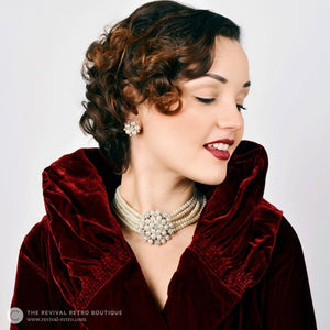 Audrey Hepburn Breakfast at Tiffany's inspired pearl earrings worn with matching necklace and a 1920s red velvet jacket by a dark haired model