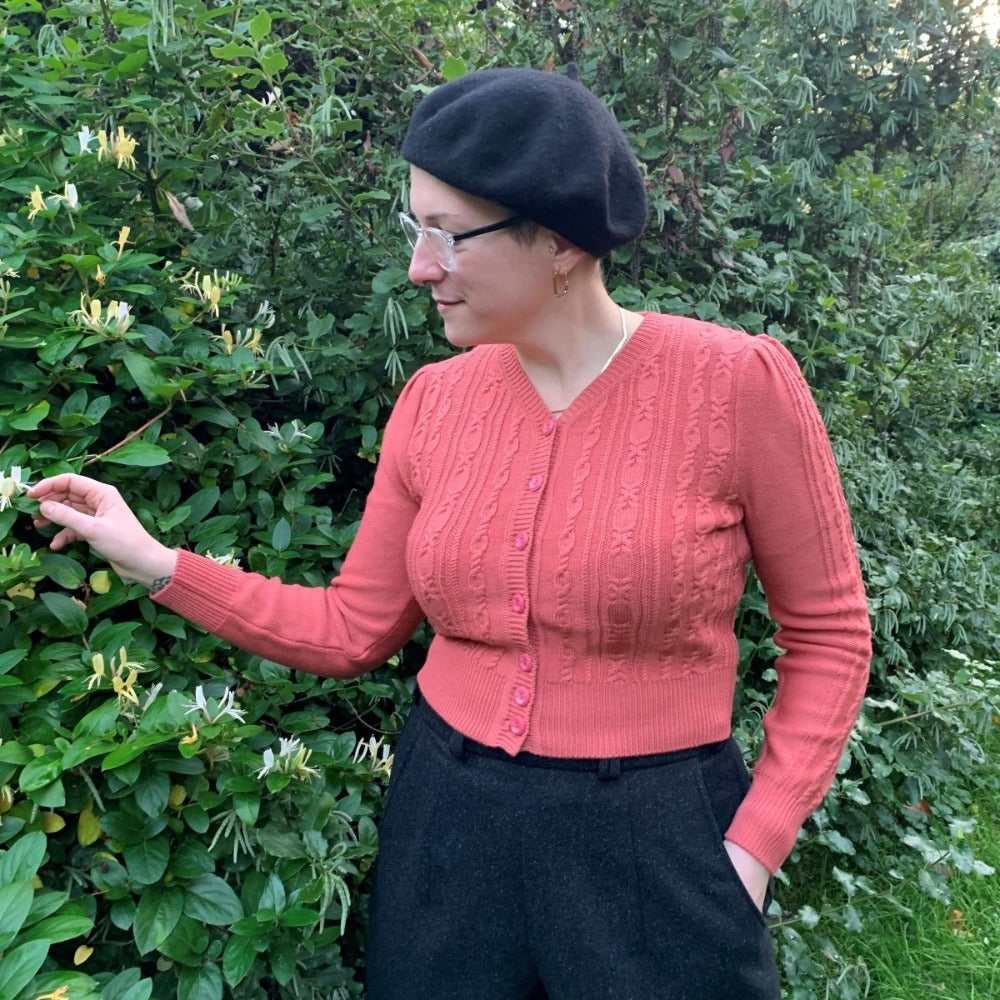 1940s style Ice Skater cardigan in salmon by Emmy Design Sweden and worn by Sarah with black Holborn trousers and black beret