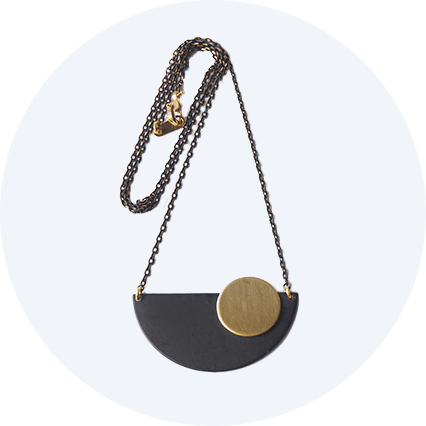 An Art Deco inspired necklace made up of a black crescent with a brass circle set off centre