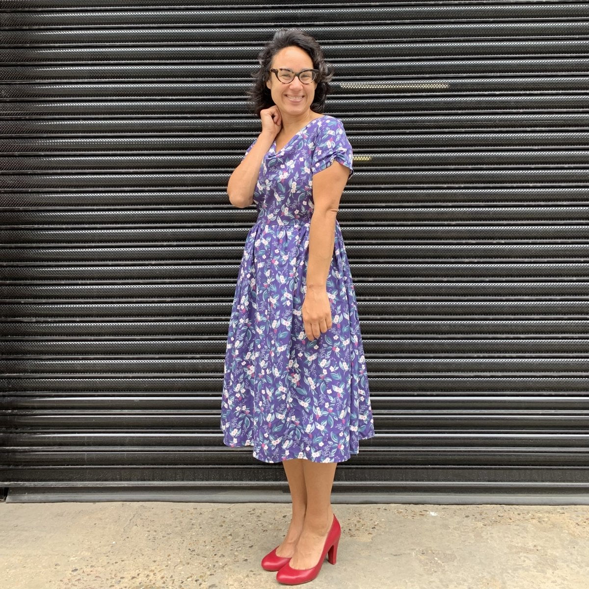 Rowena is pictured side on smiling whilst wearing a 1950s style dress in a bramble print