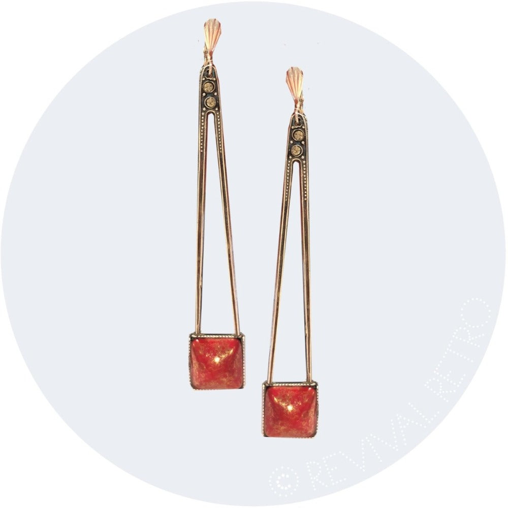 Art deco earrings featuring red stones with golden flecks, set in a silver plated structural design.