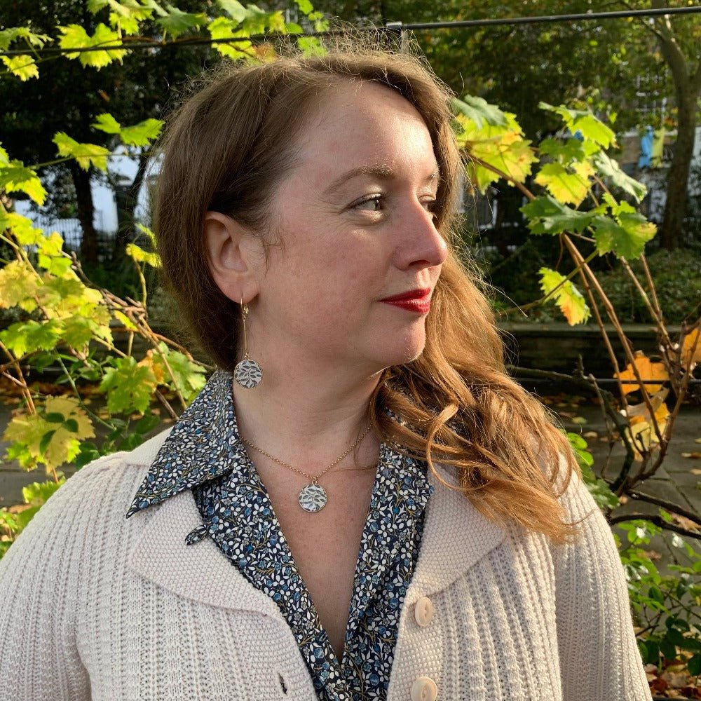 William Morris inspired earrings as worn by Mary who is side on to the camera and wearing the matching necklace and a vintage style cardigan over a floral 1940s style blouse