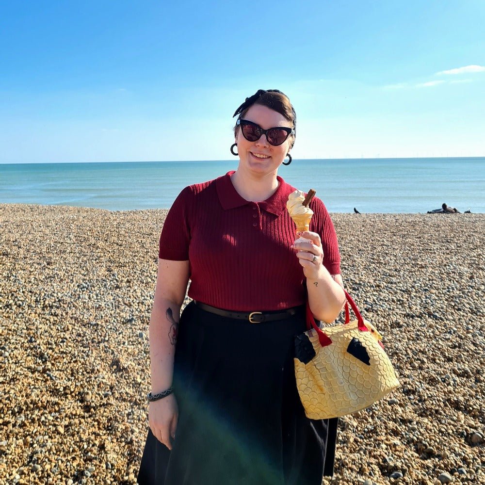 Lottie wears the burgundy Shipmate Knit Tee on Brighton Beach whilst holding a Mr Whippy ice-cream