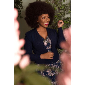Wrap dress in vintage blossom floral made in Britain by Revival Retro and worn by black vintage model Velvet Jones who has an afro and is looking to the side and smiling